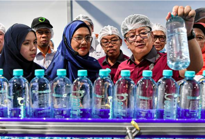 Ewon (kanan) melihat produk botol air pada majlis perasmian Pusat Pengilangan Baharu Bubbles O2 Sdn. Bhd di Kompleks Al-Ammar, Rantau hari ini