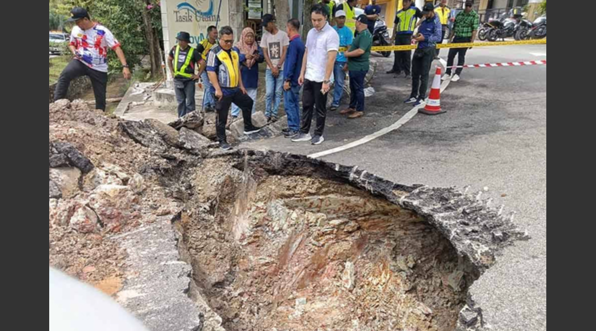 Mohamad Salzeli (kiri) dan Chee Yee melihat lubang benam sedalam dua meter di depan Balai Polis Ayer Keroh pada Sabtu. -Sinar Harian