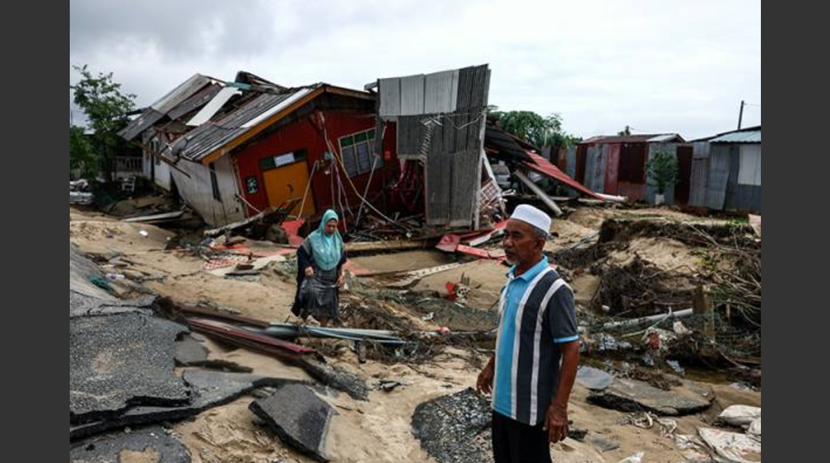 Penduduk melintasi kawasan yang musnah akibat dilanda banjir ketika tinjauan di Kampung Baru Nelayan, Tumpat, hari ini. - Gambar/ Bernama